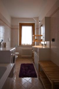 un bagno con lavandino, WC e finestra di Appartamenti Sergio Benedetti a Sappada