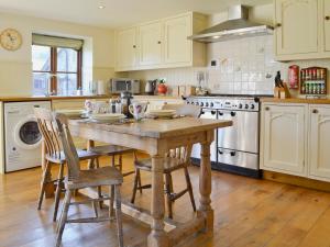 een keuken met een houten tafel en stoelen bij The Linhay in Westleigh