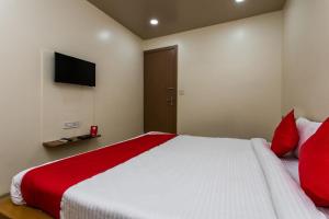 a bedroom with a bed with red pillows and a television at Hotel O Riddhi Siddhi in Indore +17 photos