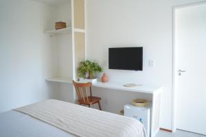 a bedroom with a bed and a desk with a tv at Casa Aia in Aracaju