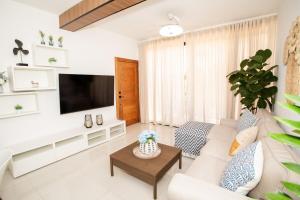 a living room with a couch and a tv at Tropical Getaway with pool & steps to the beach in Puerto Plata
