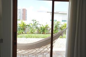 a hammock on the beach viewed from a window at Casa Aia in Aracaju +2 photos