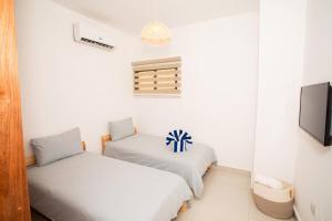 two beds in a room with a tv at Tropical Getaway with pool & steps to the beach in Puerto Plata +47 photos