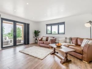 a living room with a couch and a table at Oak Tree Lodge - Uk38383 in Lyonshall