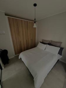 ein weißes Bett in einem Schlafzimmer mit einer Holztür in der Unterkunft Waterfall Munyaka Estate in Midrand