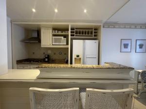 una cucina con un bancone con sedie e un frigorifero di Destino Floripa Jurerê In a Florianópolis