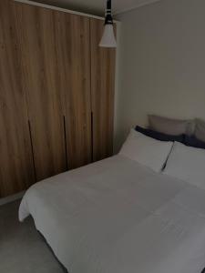Schlafzimmer mit einem weißen Bett und einem Holzschrank in der Unterkunft Waterfall Munyaka Estate in Midrand + 9 Fotos
