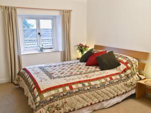 a bedroom with a bed with a quilt and a window at Shaplands Barn in Cold Ashton +3 photos