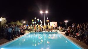 uma multidão de pessoas à volta de uma piscina à noite em Le case di Anna e Carla em Rilievo