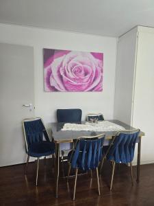 a dining room table with blue chairs and a pink painting at Queen Home1 in Lucerne