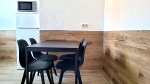 a black table and chairs with a microwave and a refrigerator at Monteurhotel Leuna in Leuna