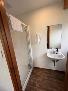 une salle de bains avec douche, lavabo et miroir dans l'établissement Kiwi Classic, à Red Beach