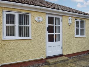 a yellow house with a white door and a clock at Pipers Stable in Nether Stowey