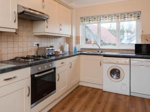 a kitchen with white cabinets and a washer and dryer at Dolphin Cottage - Uk6733 in Lydstep