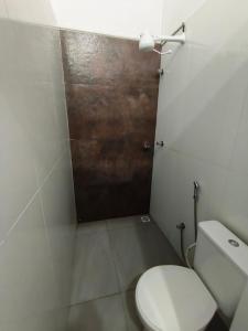 a bathroom with a toilet and a wooden door at Lar Doce Lar Realizando Sono!!! in Arcos