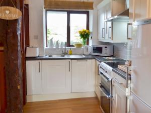 a kitchen with white cabinets and a sink and a window at Discovery in Cheriton Bishop