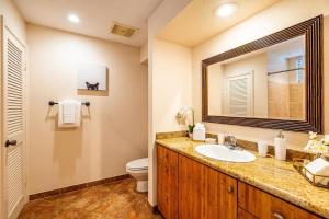 a bathroom with a sink and a toilet and a mirror at Serene Maui Retreat Walk to Beach & Shops in Wailea