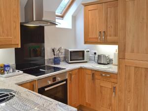 a kitchen with wooden cabinets and a microwave oven at The Old Vicarage in Curbar