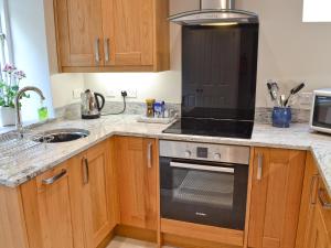 a kitchen with wooden cabinets and a stove top oven at The Old Vicarage in Curbar