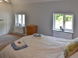 a bedroom with a large white bed with two windows at The Old Vicarage in Curbar +8 photos