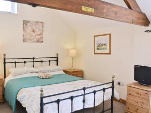 een slaapkamer met een bed en een flatscreen-tv bij The Milking Parlour - 18436 in Bempton