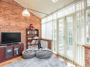 een woonkamer met een tv en een bakstenen muur bij Edderton Hall Country House in Forden