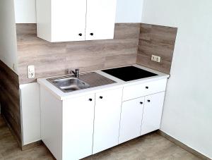 a small kitchen with white cabinets and a sink at Monteurhotel Leuna in Leuna