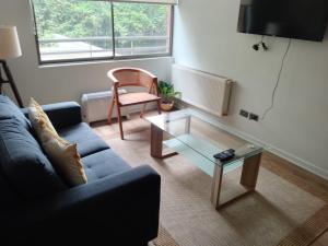 Una sala de estar con un sofá azul y una mesa de cristal. en Exclusivo depto con AC y piscina Ñuñoa, en Santiago