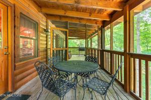 a wooden porch with a table and chairs on it at Along the Trail Cabin with Hot Tub Pool Pond Game Room in Wear Valley