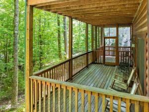 a wooden porch of a cabin in the woods at Along the Trail Cabin with Hot Tub Pool Pond Game Room in Wear Valley +20 photos