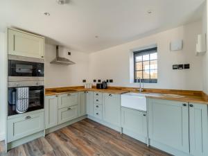 a kitchen with white cabinets and a sink at Stable View Barn - Uk45938 in Corley
