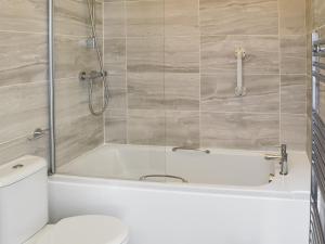 een badkamer met een wit bad en een toilet bij Shyre Stable - 18437 in Bempton +6 foto's