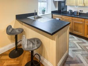 una cucina con un bancone e due sgabelli di Marsay Cottage a Loftus