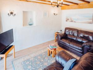 a living room with leather furniture and a flat screen tv at The Bakery - Uk6727 in Lydstep