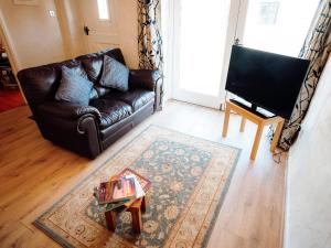 a living room with a leather couch and a coffee table at The Bakery - Uk6727 in Lydstep