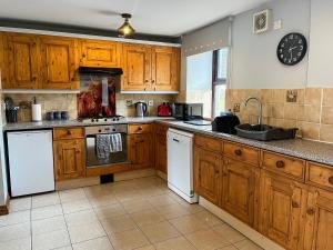 a kitchen with wooden cabinets and a clock on the wall at Tom Wragg Suite - Uk40248 in Bakewell