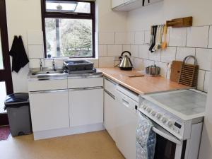 a white kitchen with a sink and a stove at Ghyllside 3 in Ambleside