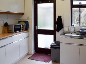 a kitchen with a door and a sink and a microwave at Ghyllside 3 in Ambleside