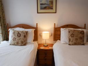 a bedroom with two beds and a table with a lamp at Ghyllside 3 in Ambleside
