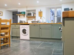 eine Küche mit grünen Schränken und einer Waschmaschine und einem Trockner in der Unterkunft Ivy Cottage - Tq4 in Boscastle
