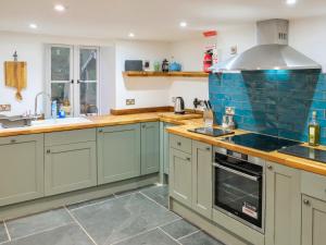 Eine Küche mit grünen Schränken und blauen Fliesen in der Unterkunft Ivy Cottage - Tq4 in Boscastle