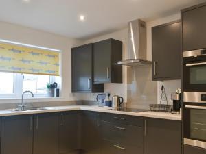 a kitchen with gray cabinets and a sink and a window at Ad Gefrin in Acklington