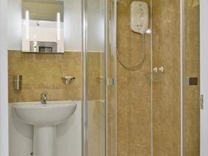 a bathroom with a shower with a sink and a toilet at 5 Balmoral House in Keswick
