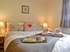 ein Tablett mit Essen auf einem Bett mit Handtüchern und Gläsern Orangensaft in der Unterkunft Ty Newydd Cottage in Hoel-galed