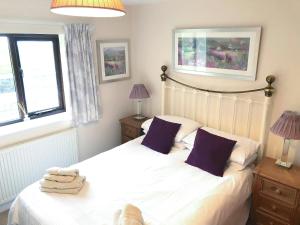 a bedroom with a white bed with purple pillows at Chapman House in Parkham +11 photos