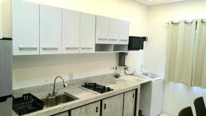 a kitchen with white cabinets and a sink at Studio Centro Coité in Conceição do Coité