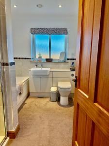 ein Badezimmer mit Waschbecken und Toilette und einem Fenster in der Unterkunft Golf View Spacious Bungalow 2 Bathrooms, Free Parking WiFi in Elgin