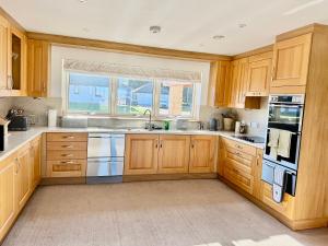 eine Küche mit Holzschränken und einem Fenster in der Unterkunft Golf View Spacious Bungalow 2 Bathrooms, Free Parking WiFi in Elgin