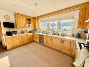 eine Küche mit Holzschränken und Spüle und einem Fenster in der Unterkunft Golf View Spacious Bungalow 2 Bathrooms, Free Parking WiFi in Elgin + 8 Fotos