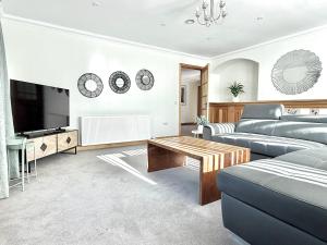 ein Wohnzimmer mit Sofa und Fernseher in der Unterkunft Golf View Spacious Bungalow 2 Bathrooms, Free Parking WiFi in Elgin